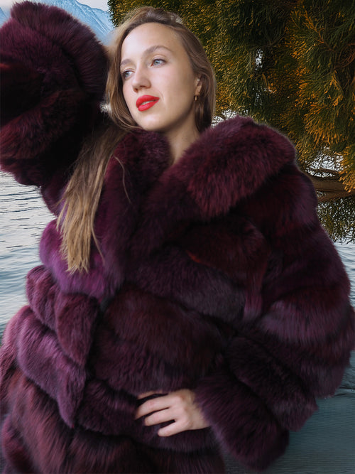 Woman wearing a dark purple fur coat with a blurred natural background