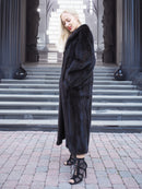 Elegant black mink fur coat on woman, full-length winter fashion accessory.
