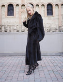 Luxurious black mink fur coat styled in elegant urban setting.