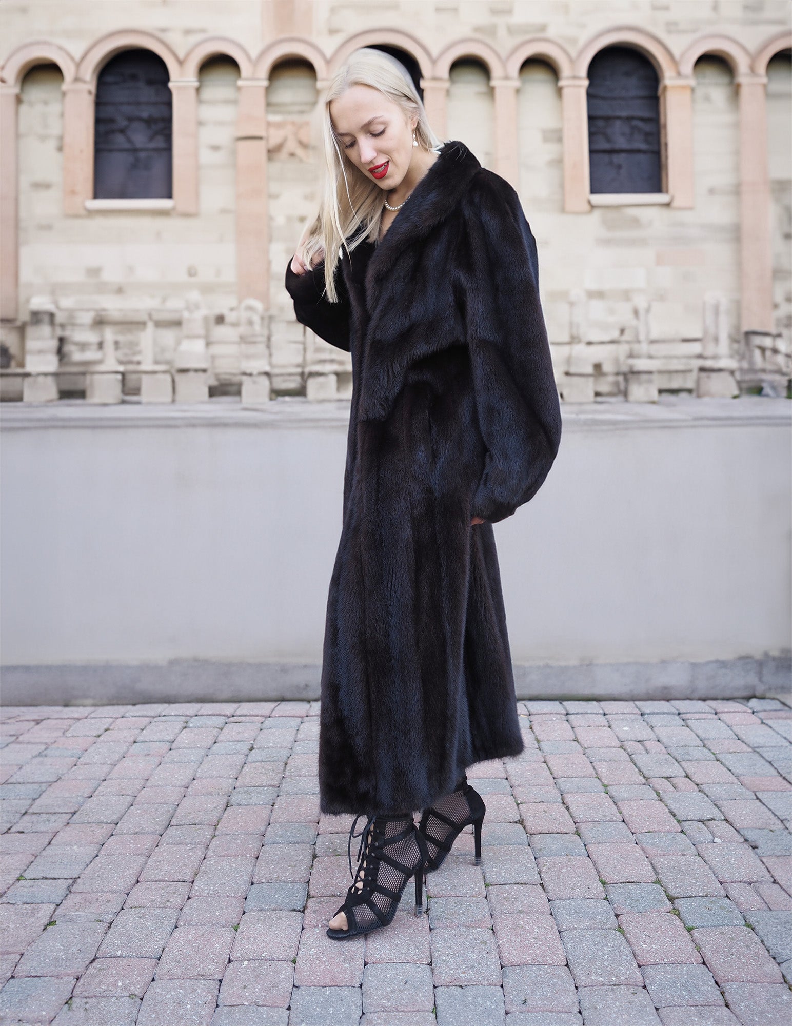 Luxurious black mink fur coat styled in elegant urban setting.