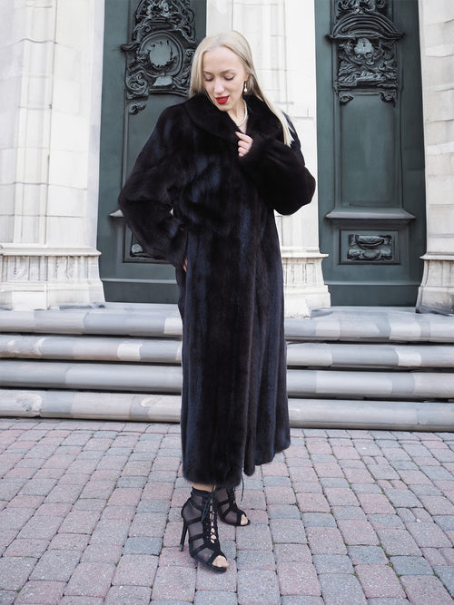 Elegant black mink fur coat, woman standing on stairs against ornate building entrance