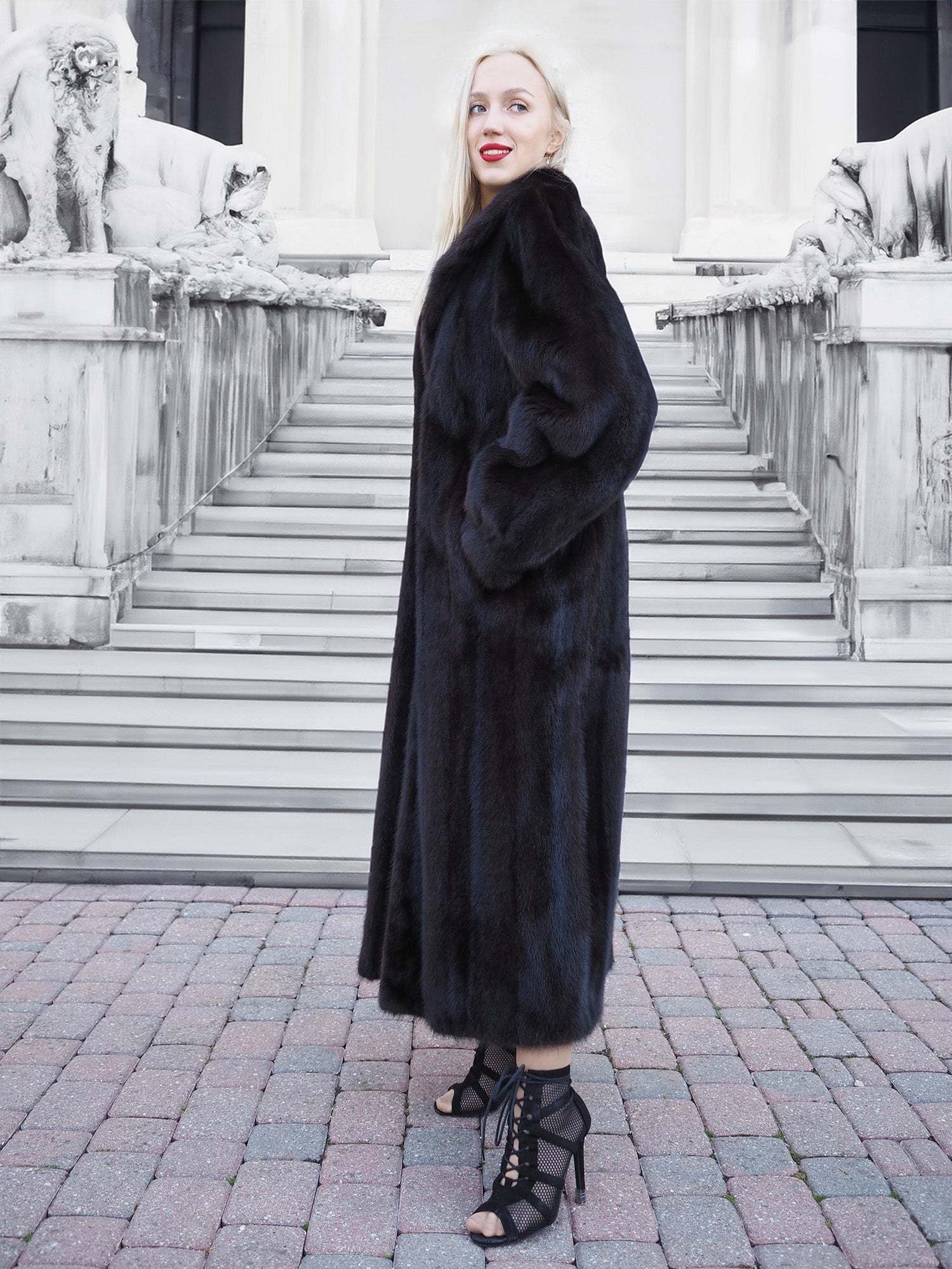 Luxurious black mink fur coat, elegant woman posing on stairs, high-fashion attire