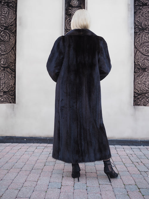 Luxurious black mink fur coat, featuring full-length styling and a plush, high-quality appearance, showcased against a modern architectural backdrop.