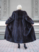 Luxurious black mink fur coat with elegant design and tailored fit, showcased against an ornate architectural background.