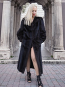 Stylish black fur coat worn by young woman in front of stone columns