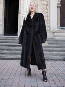 Luxurious black mink fur coat, full-length design, elegant woman posing on stairway, premium winter fashion accessory.