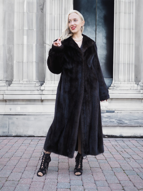 Elegant black mink fur coat on model posing outdoors in front of columns
