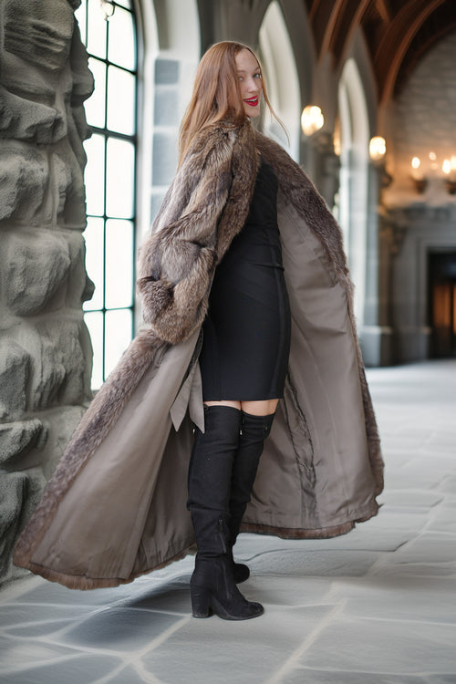 Woman wearing a long fur coat in an indoor setting with stone walls and large windows.