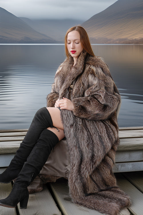 Woman in a fur coat sitting on a dock with a scenic background