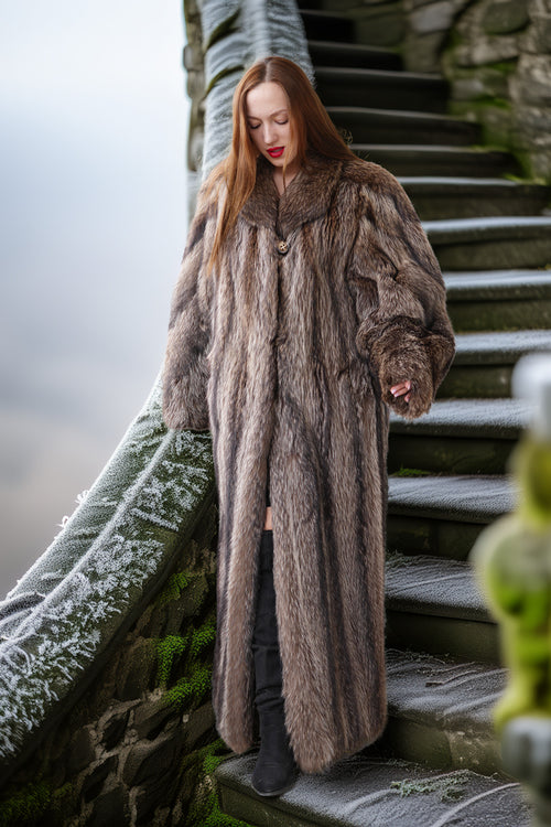Woman in a fur coat standing on stone steps with a snowy landscape.