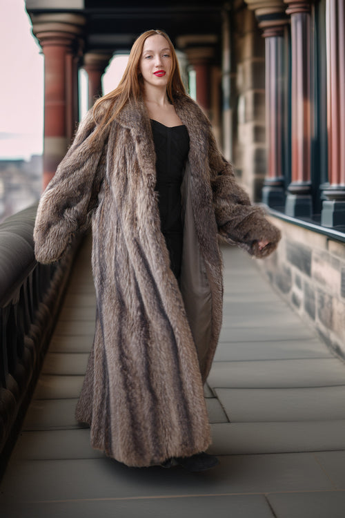 Woman wearing a long fur coat on a city street.
