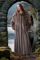 Woman in a fur coat standing through a stone archway with a scenic background
