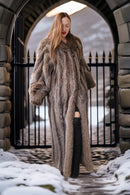 Woman in a fur coat standing in a snowy landscape with stone archway.