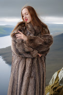 Woman wearing a fur coat with a mountainous landscape in the background