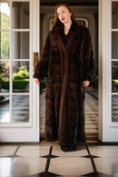 Woman wearing a long brown fur coat standing in a doorway.