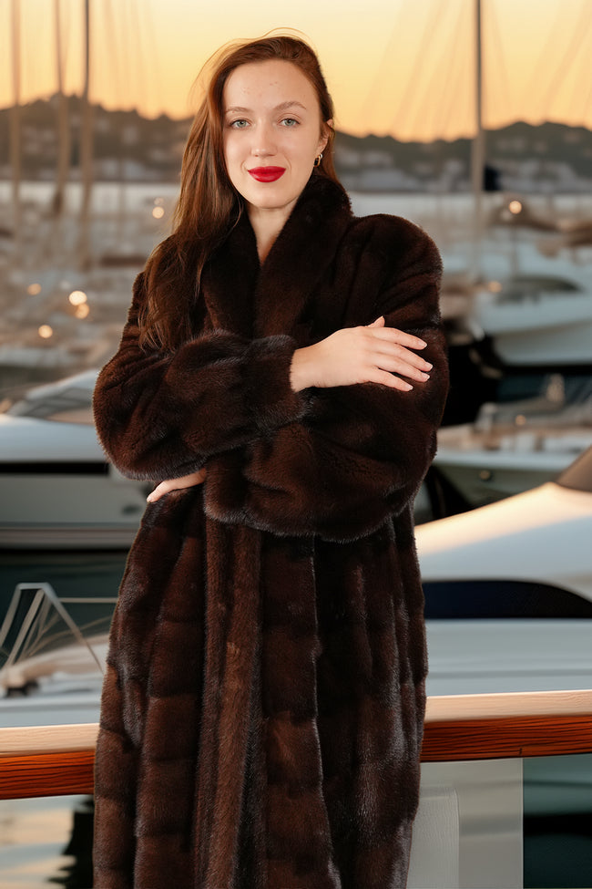 Woman wearing a brown fur coat standing by a marina with boats in the background.