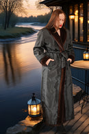 Woman in a long coat standing by a waterfront at dusk with lanterns.