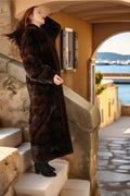 Woman in a fur coat standing on stone steps with a scenic background