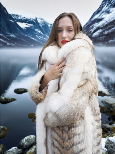 Coyote fur coat with white fox trim by a lake