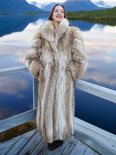 Timeless Vintage Coyote Fur Coat in Wild Luxury, full-length with voluminous fur, worn beside a serene alpine lake.