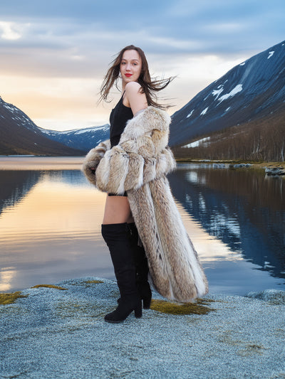 Coyote Fur Coat styled open over a black outfit, worn beside a tranquil lake at sunset, showcasing Wild Luxury.