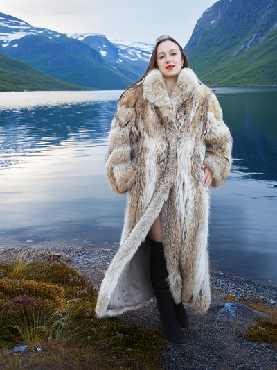 Vintage Coyote Fur Coat with full-length silhouette and plush collar, styled in a rugged outdoor setting by a lake.