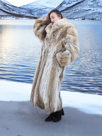 Authentic Coyote Fur Coat, 50" long with voluminous texture, worn on icy terrain beside a winter lake.