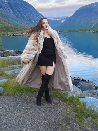 Coyote Fur Coat 50" Long, styled open over a black dress, showcasing luxury fur fashion in a mountain lake setting.