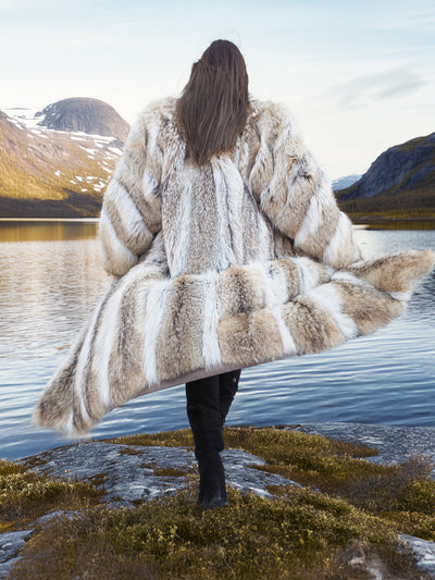 Back view of Vintage Coyote Fur Coat in Wild Luxury, showcasing rich fur pattern and dramatic movement by a mountain lake.