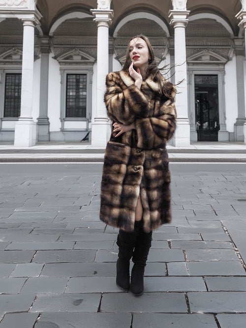 Long fur coat with horizontal striped pattern and button detail at the waist