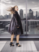 Woman in a fur coat standing on a rooftop with a cityscape in the background