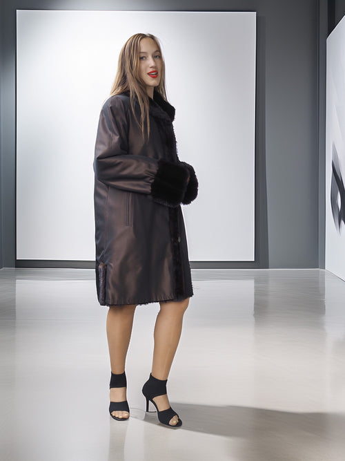 Woman wearing a black leather coat with fur trim in a studio setting
