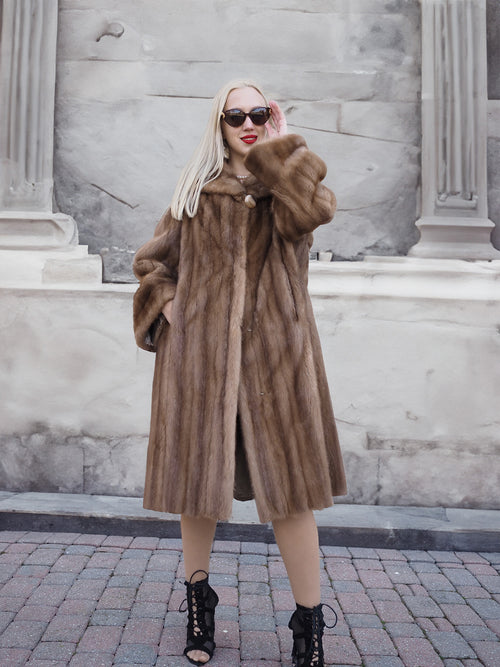 Stylish pastel brown mink fur coat on model against stone building