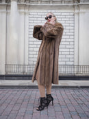 Elegant vintage Canadian brown mink fur coat stroller showcased against a white brick building facade.