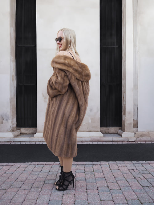 Elegant beige mink fur coat, woman standing in front of black and white backdrop