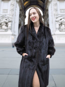Smiling woman in black mink fur coat with front slit and wing collar, showcasing refined cold-weather fashion.