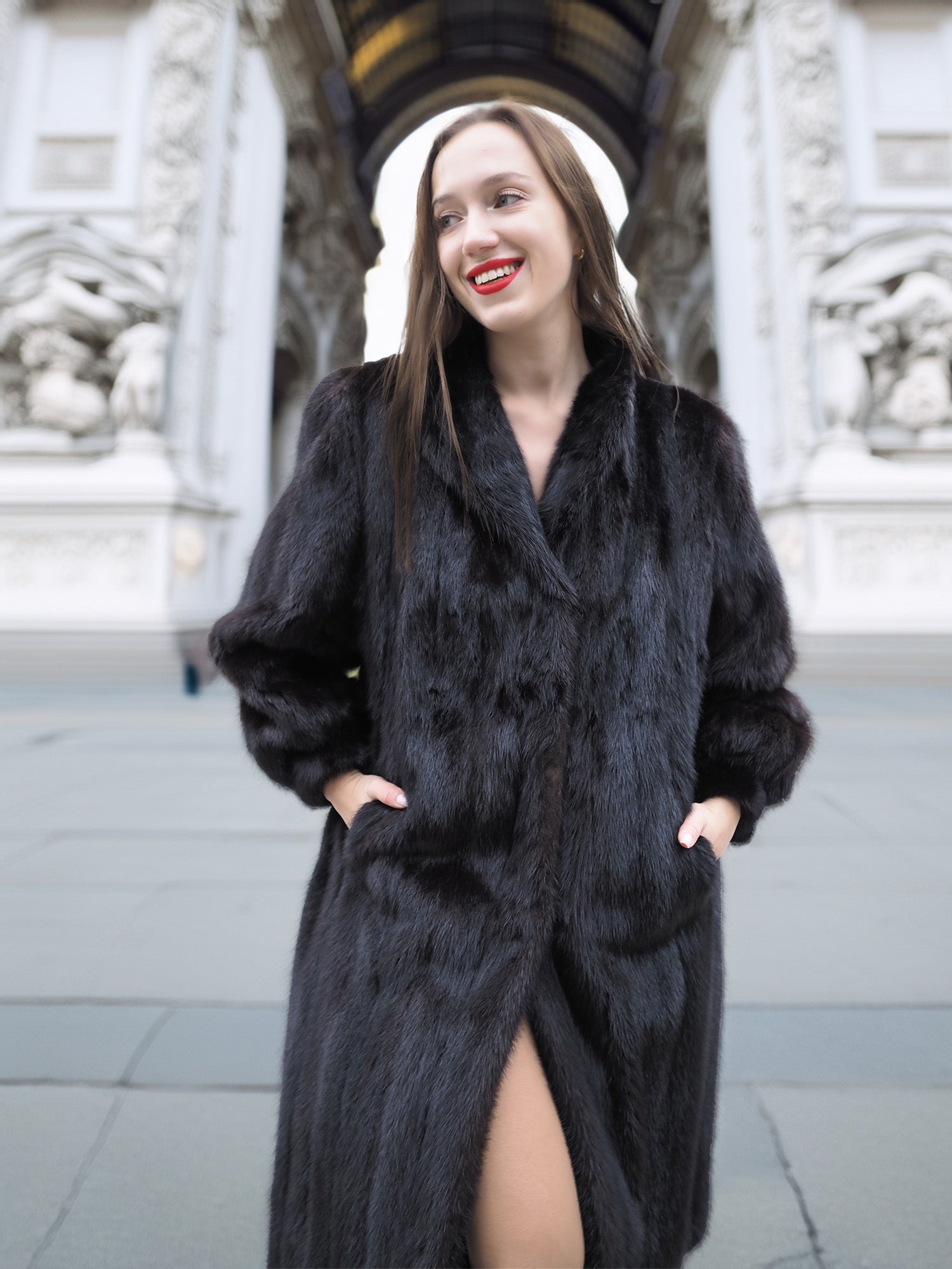Smiling woman in black mink fur coat with front slit and wing collar, showcasing refined cold-weather fashion.