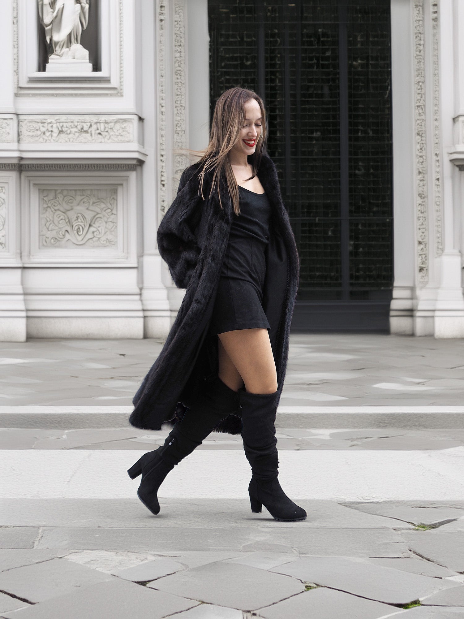 Woman walking in open black mink fur coat over a black dress, showcasing versatile styling for winter fashion.