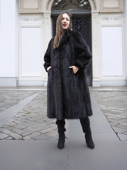 Full-length black mink fur coat with side pockets and structured silhouette, designed for sophisticated cold-weather wear.
