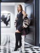 Woman in a stylish outfit with a fur coat standing in a modern interior setting.
