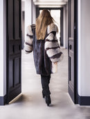Person wearing a fur coat walking down a hallway