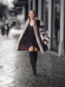 Woman in a fur coat and black dress walking on a city street.