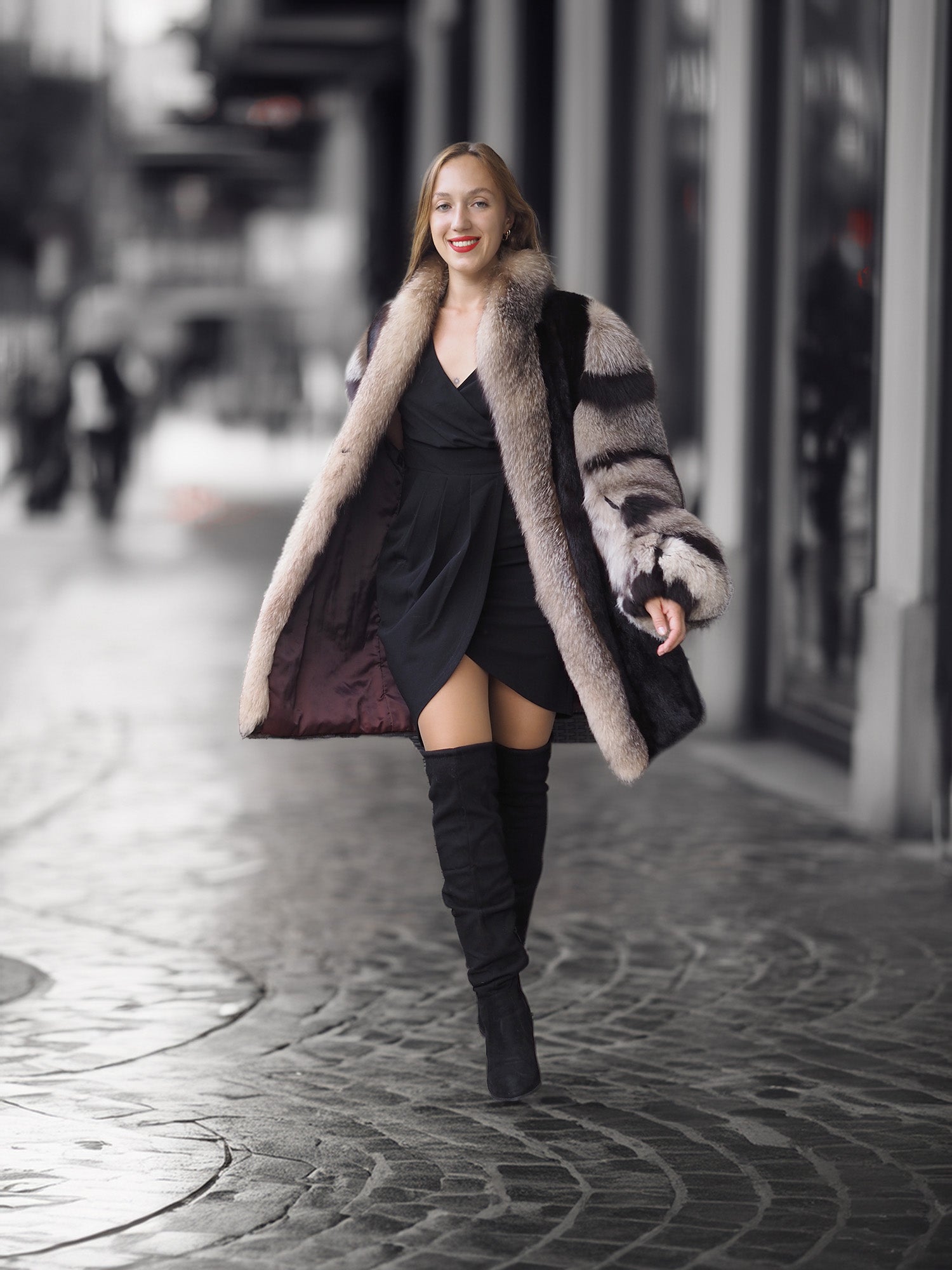 Woman in a fur coat and black dress walking on a city street.