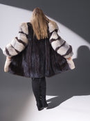 Person wearing a fur coat with a striped pattern on a plain background