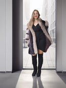 Woman wearing a fur-lined coat and black boots in an urban setting