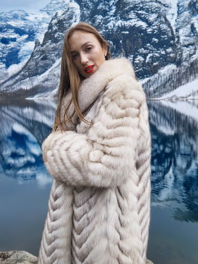 Luxurious blue fox fur coat with chevron design by waterfront.