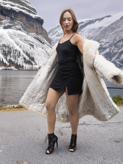 Elegant blue fox fur coat with shawl collar in snowy mountains.