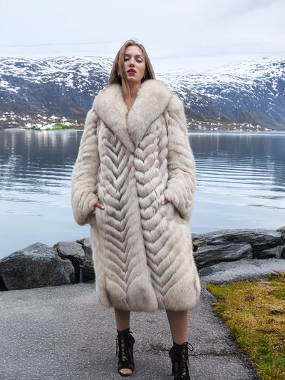 Blue fox fur coat with chevron pattern by a serene lake.