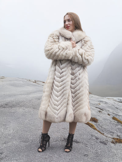 Plush blue fox fur coat with large collar in misty mountains.