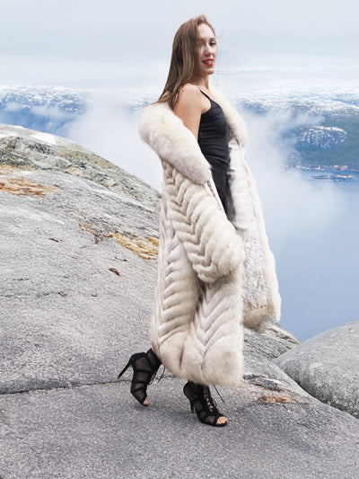 Blue fox fur coat with elegant shawl collar on a rocky path.